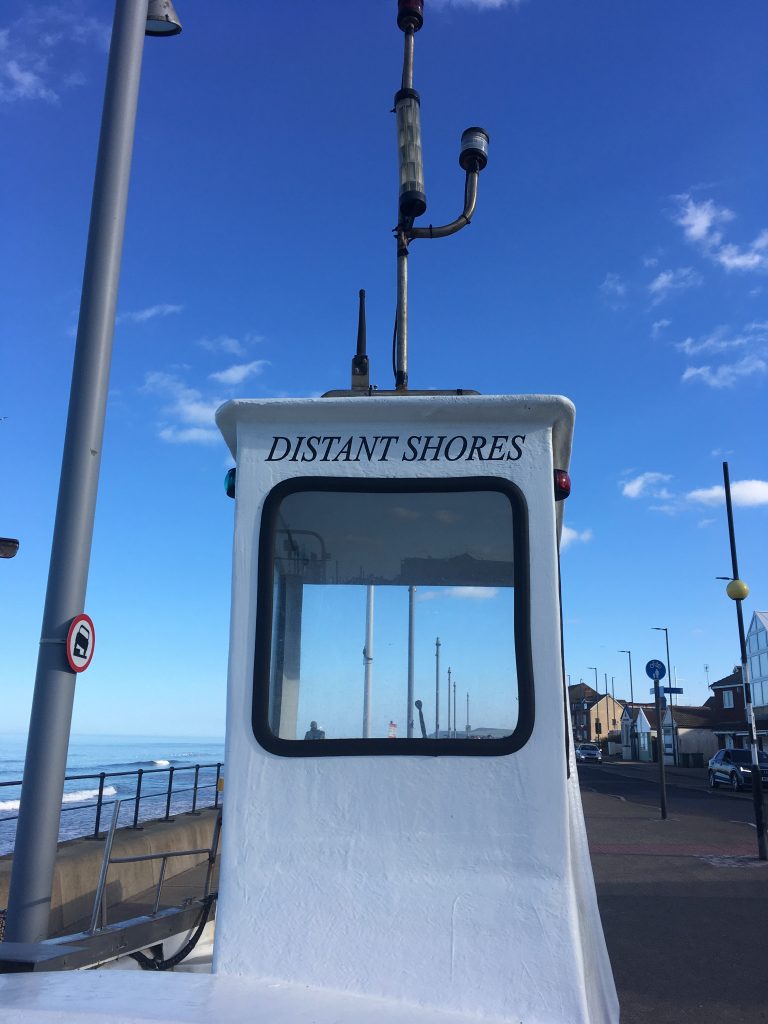Boat on the shore at Redcar with the name Distant Shores in blue letters on the cabin